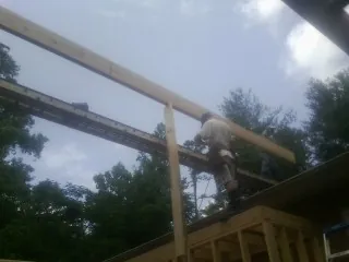 Carpenter setting a ridge beam over a new addition frame — Ice Dam Removal by Roofing Brothers in Hooppole