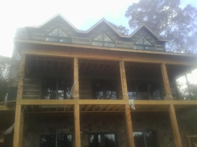 Dormers and porch framing on a large log home under construction — Roof Coating work by our crew in Hooppole