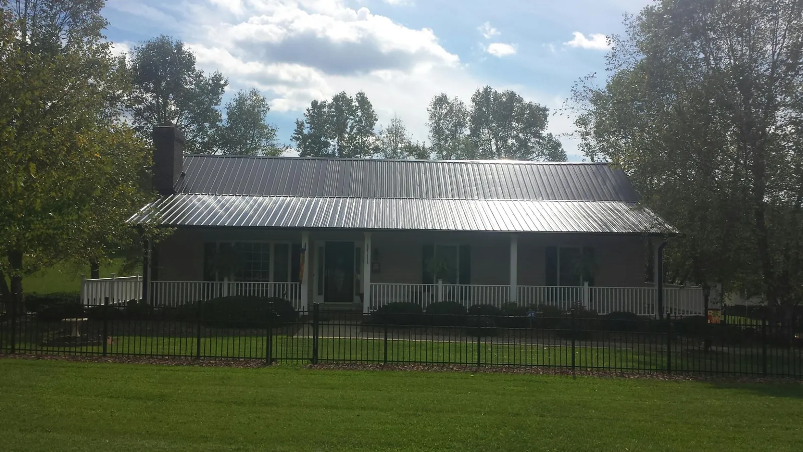 Gray metal roof on a brick ranch with a full width front porch — Gutter Guard Installation work by our crew in Hooppole