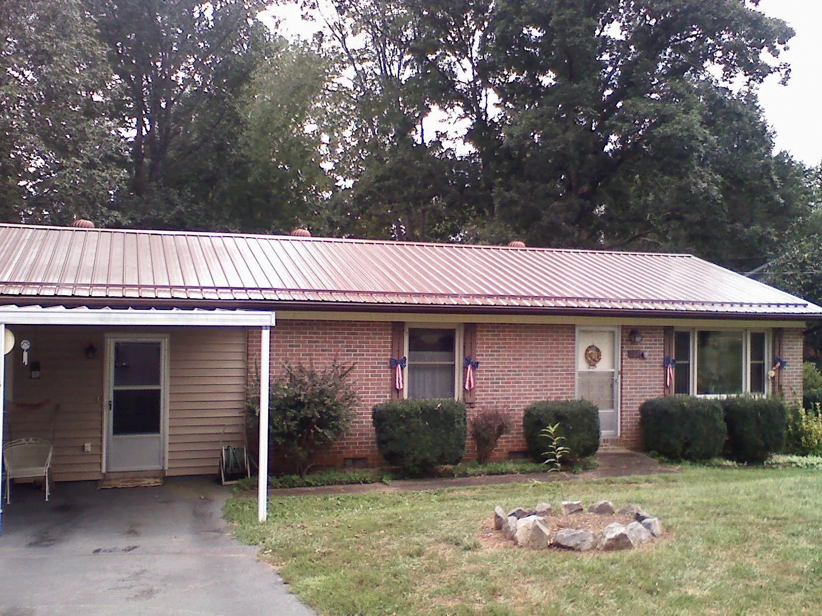 Bronze metal roof and carport on a brick ranch home — Roof Repair work by our crew in Hooppole
