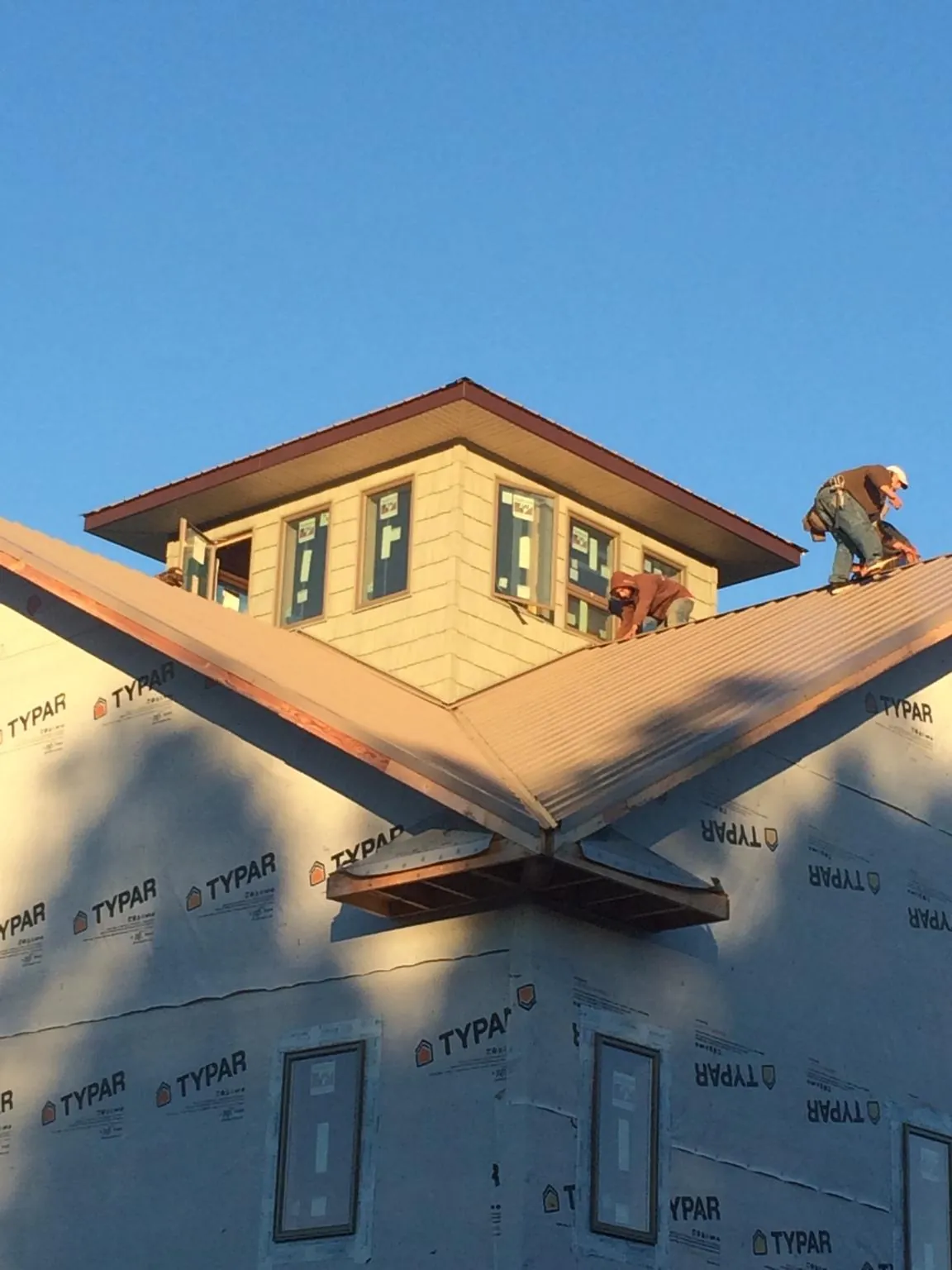 Roofers working around a rooftop cupola on a new metal roof at sunset — Roof Waterproofing in Hooppole by Roofing Brothers